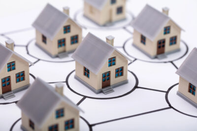 HOA Safety and Security Tips - tiny toy houses are arranged on a white background and grid.